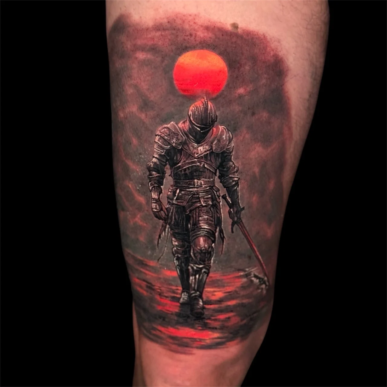 Colour dark fantasy thigh tattoo of an armoured knight with a sword before a glowing red sun at Bloodline Tattoo Bangkok.
