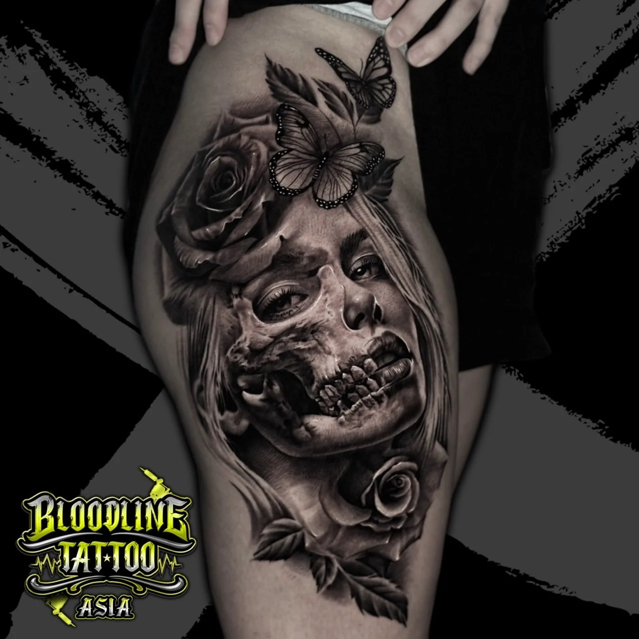A black and grey realism thigh tattoo of a woman's face merging into an anatomical skull, framed by roses and monarch butterflies, at Bloodline Tattoo Bangkok.